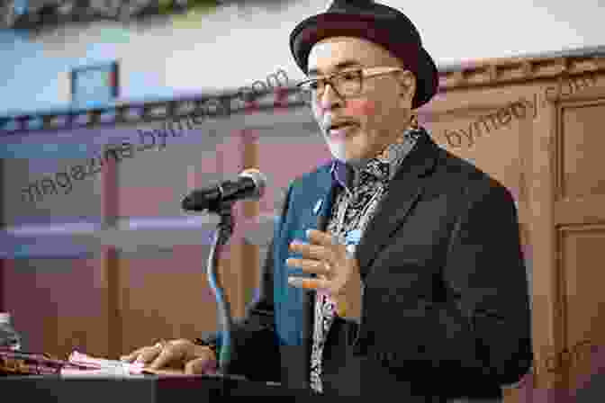 Juan Felipe Herrera Reading Poetry At A Podium, Wearing A Suit And Glasses Imagine Juan Felipe Herrera